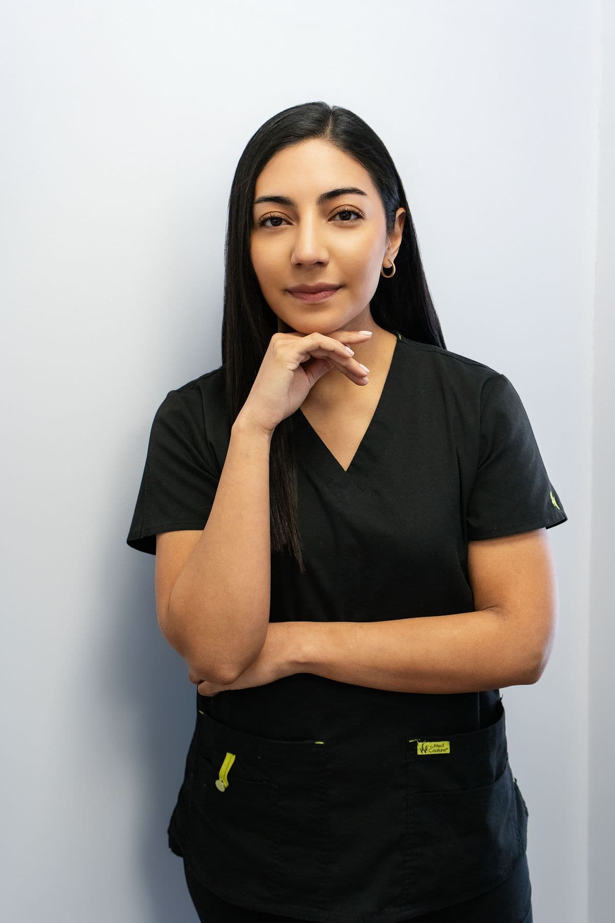 Dentist in black scrubs photographed against a neutral background