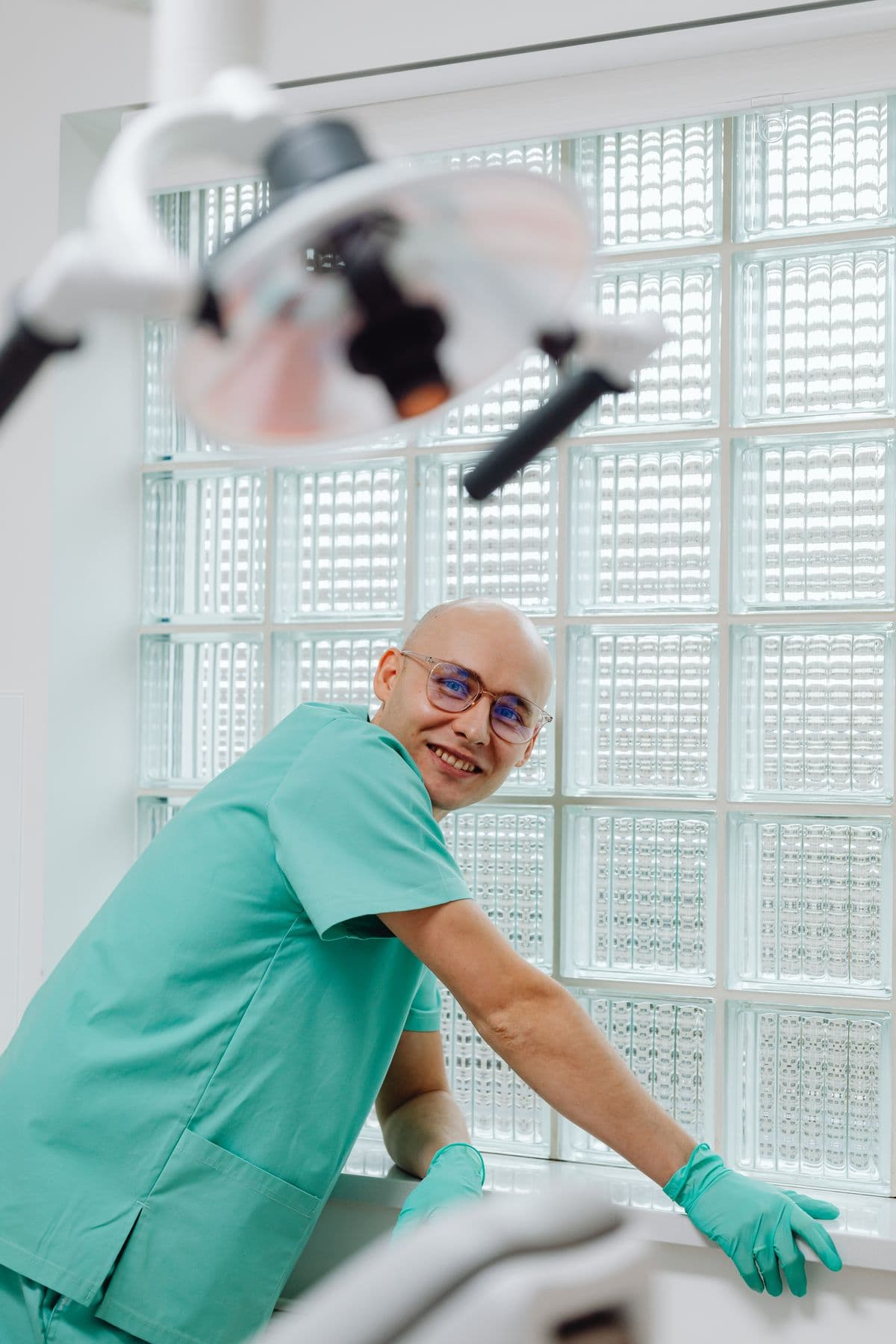 Dentist in green scrubs in a bright treatment room