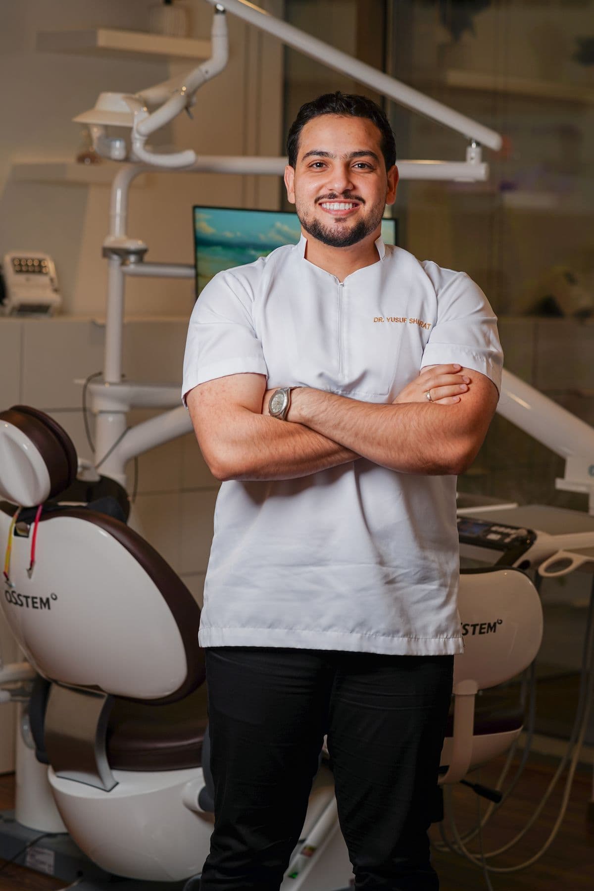 Dental clinician in a white uniform standing in a treatment room