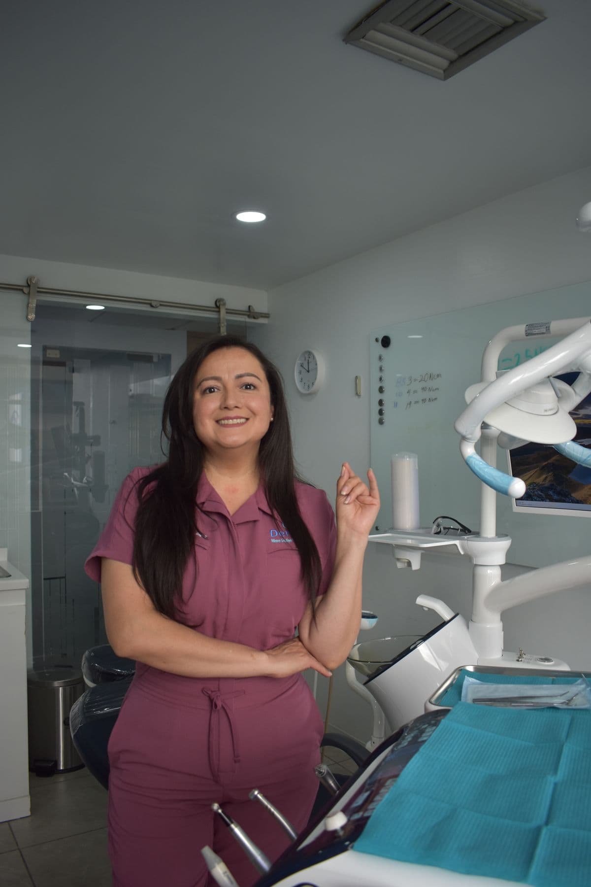 Dentist in burgundy scrubs standing in a modern treatment room